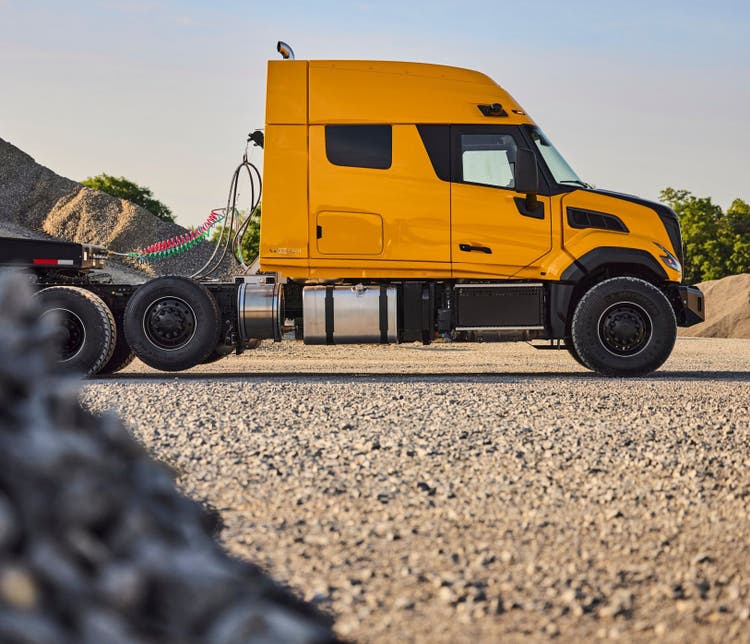 A side view of a yellow Volvo VNX Heavy-Haul on a rocky background.