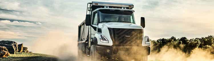 A front view of the Volvo VNX on a dustry road. With dusty smmoke on the ground around the truck.