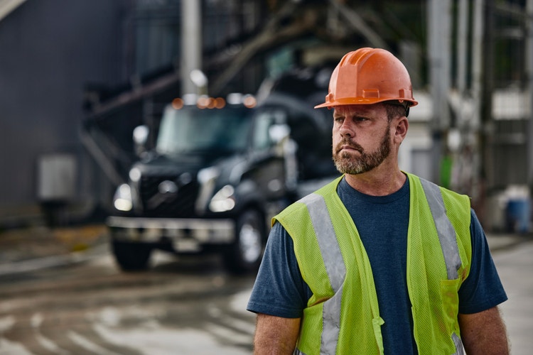 A construction worker with the Volvo VNX behind him in the background