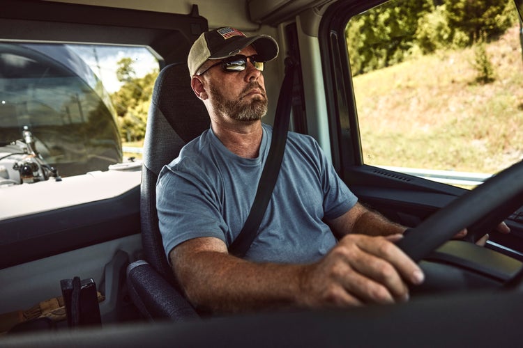 A man with his hands on the steering wheel driving a Volvo VNX comfortably.