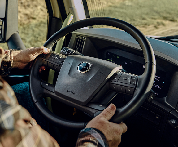 A ckise up view of a driver on behind the wheel with his hands on the steering wheel.