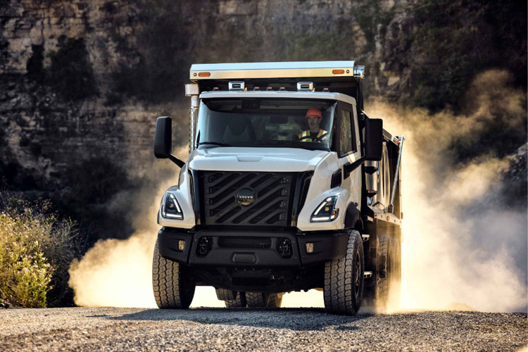 A front view of the Volvo VNX with a driver behind the wheel and smoke from the tires that are behind the truck.