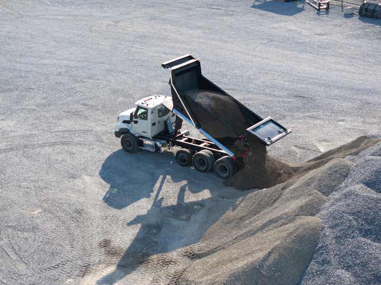 A drone view of the Volvo VNX dumoing sand behind it.