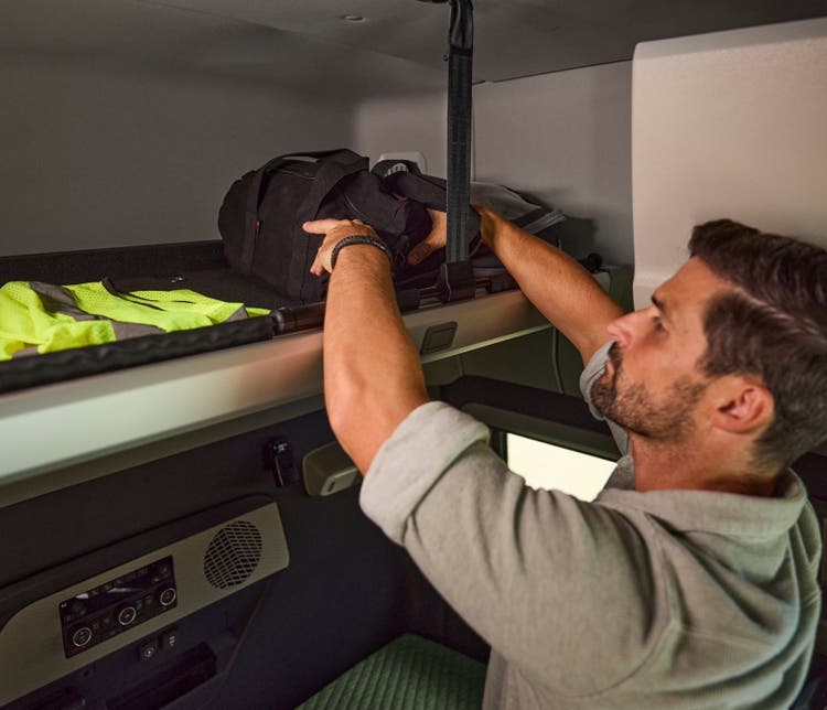 A man storing his luggage comfortably in the space available inside the Volvo VNX