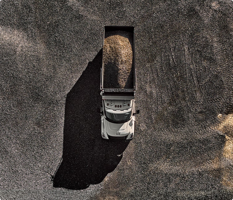 A view from above of the Volvo VNX Dump truck with sand or gravel at the back.