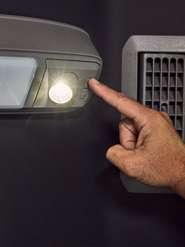 A view of the intelligent lighting option available in the Volvo VNX. A finger prssing a button next to the light.