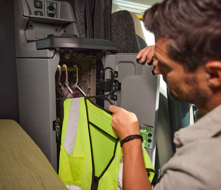A man adjusting his belongings inside the solid cabinet of the Volvo VNX truck